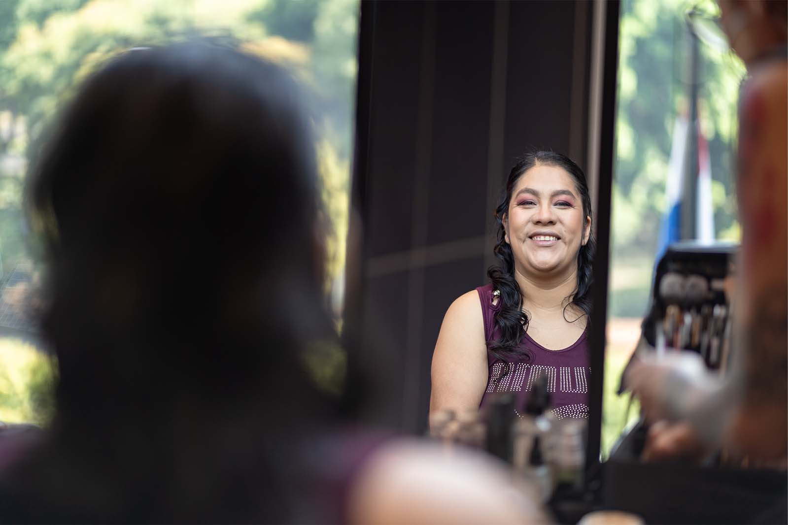Magali Pedro sonriente frente al espejo mientras se prepara.