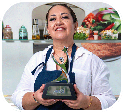 Petra Godoy ganadora del Premio Emprendedores 2024, sosteniendo el trofeo en un restaurante.