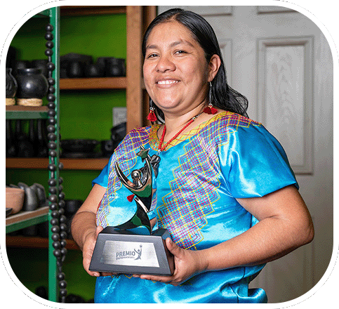 Magali Pedro en 2024, con trofeo en mano y blusa tradicional en una tienda de cerámica.