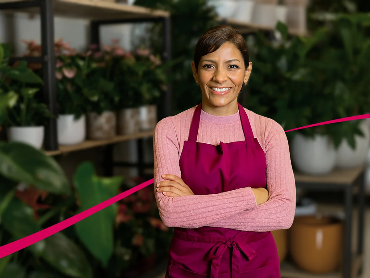 Señora sonriendo de brazos cruzados en tienda de flores