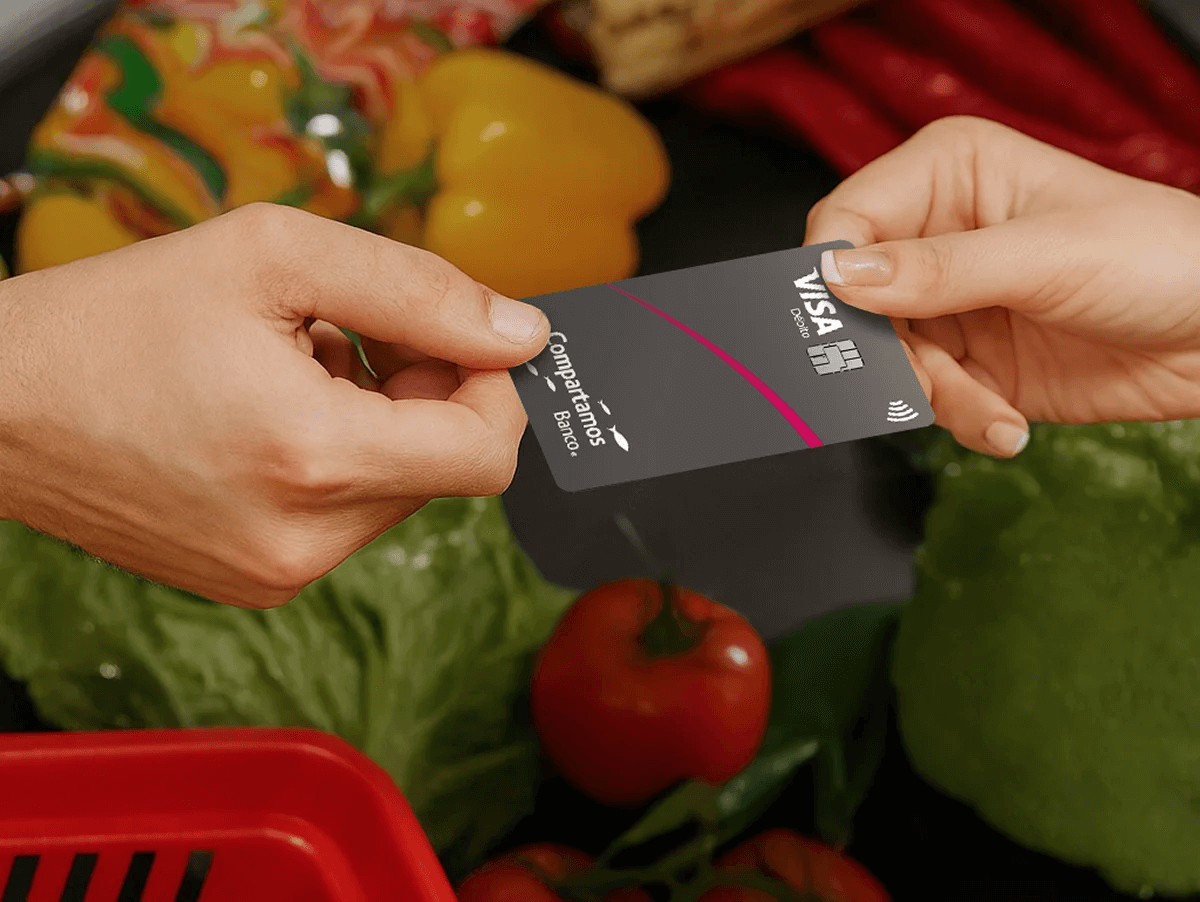 Tarjeta compartamos banco sostenida por 2 manos