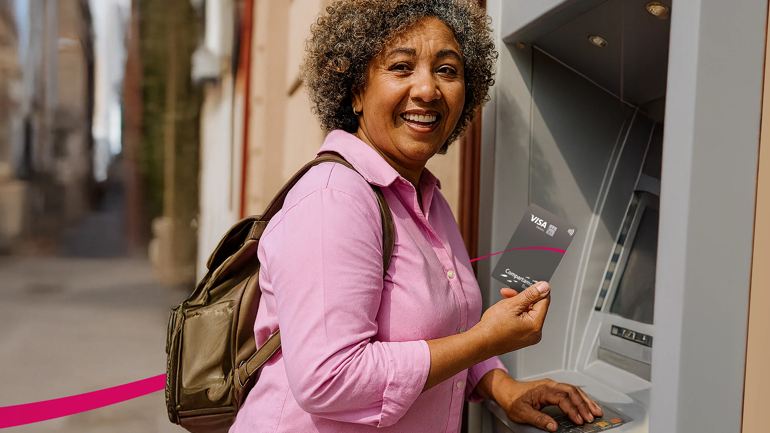 Señora sosteniendo Tarjeta Compartamos Banco junto a ATM